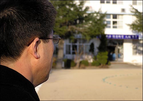 사립학교의 내부고발자 김중년씨가 먼발치에서 학교를 바라보고 있다. 그는 "비리없고 아름다운 학교로 복직하고 싶다"고 말했다. 